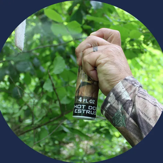 A hunter holding up a bottle of RAW Hot Doe Estrus in the woods