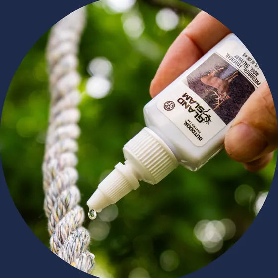A drop of Gland Slam deer scent falling from the bottle onto a rope